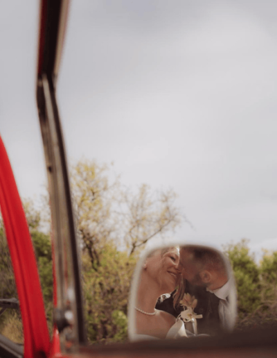Romantic reflection of a bride and groom sharing a moment in a vintage car mirror during their wedding in Croatia.