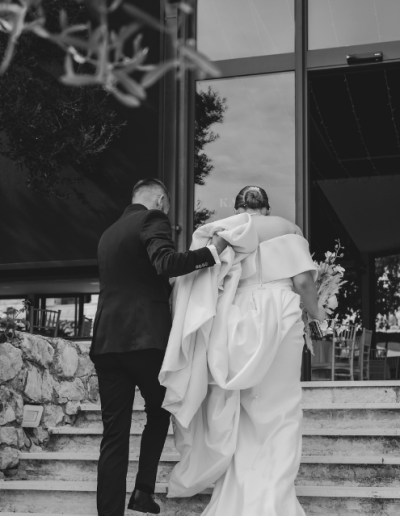 Bride and groom walking up the steps together into their wedding venue in Croatia, holding hands and bouquet.